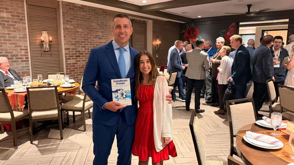Richard C. Wilson with his daughter holding Centimillionaire Strategies at a member dinner